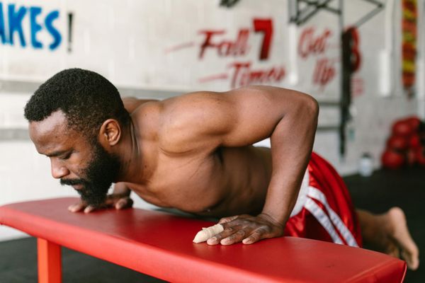 Man performing a controlled bodyweight squat in a minimalist gym.
